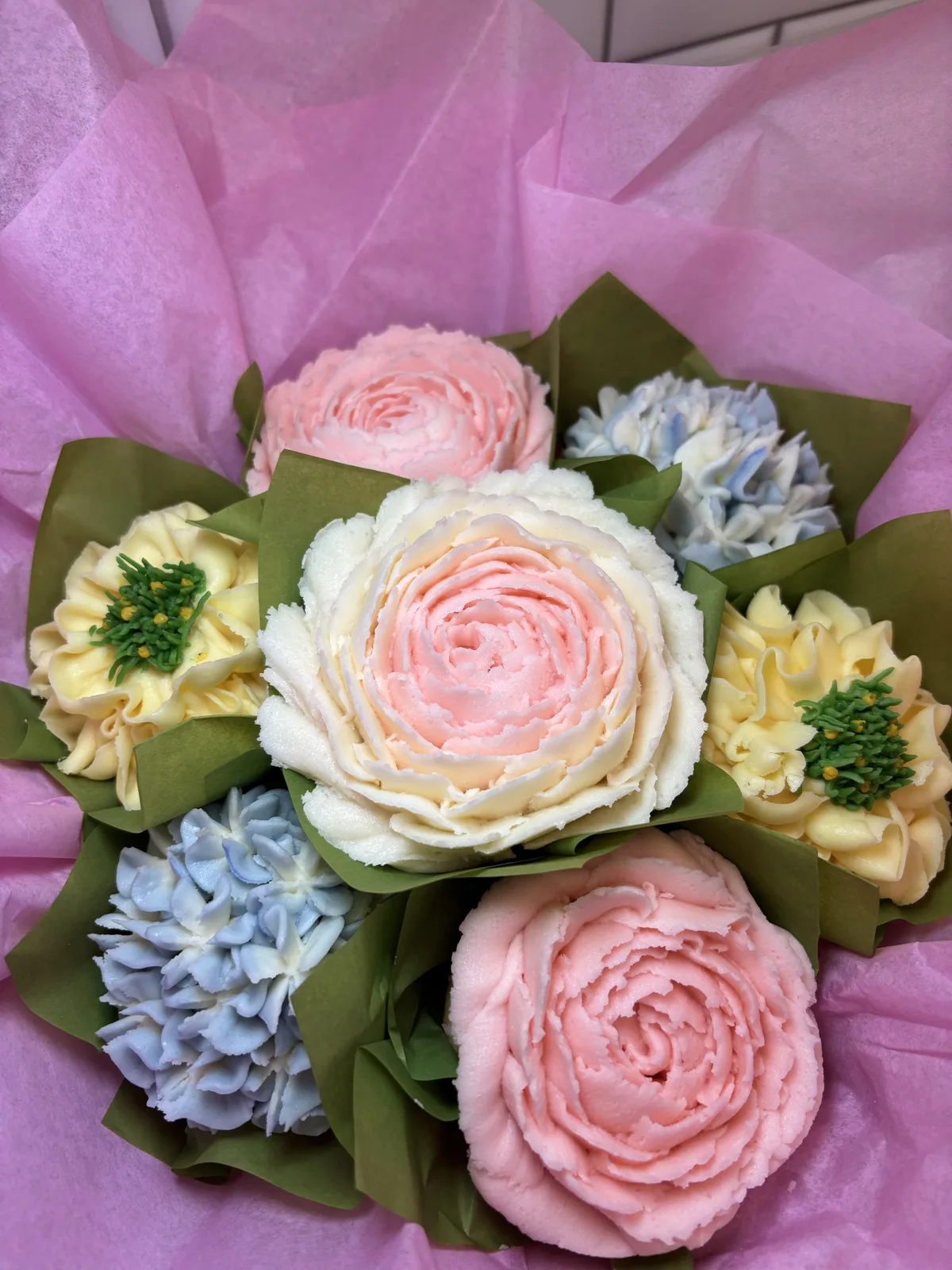 Pink, yellow, and blue blooming cupcakes arranged on a tiered stand